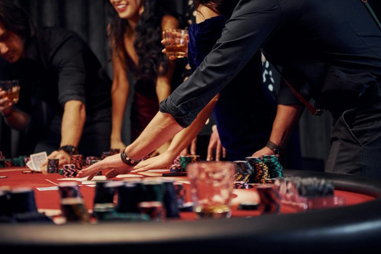 People in elegant clothes standing and playing poker in casino together
